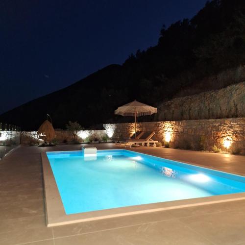 a swimming pool at night with a stone wall at Azzurro Mare in Póndi