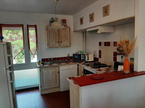 une cuisine avec des placards blancs et un comptoir rouge dans l'établissement T3 à Vieux-Boucau-Les-Bains - quartier calme entre commodités et plages - FR-1-239-1134, à Vieux-Boucau-les-Bains