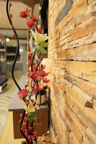 a vine of red flowers hanging from a brick wall at AG Home - Kampala in Kampala