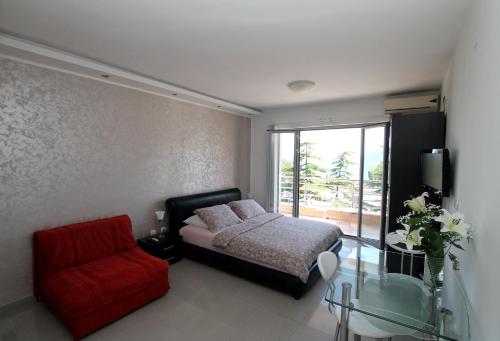 a bedroom with a bed and a chair and a glass table at Montesun Residence in Herceg-Novi