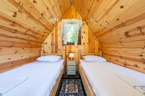 two beds in a log cabin bedroom with a window at NAJ village in Cetinje