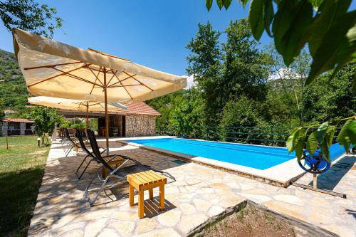 a swimming pool with an umbrella and a table and chairs at NAJ village in Cetinje