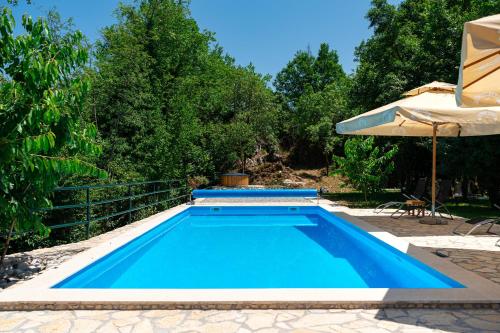 a blue swimming pool with an umbrella and an umbrella at NAJ village in Cetinje