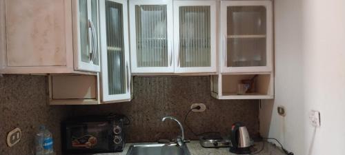 a kitchen with white cabinets and a sink at Porte Hotel in Az Za‘farānah