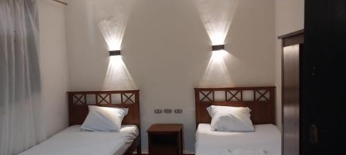 two beds in a room with two lights on the wall at Porte Hotel in Az Za‘farānah