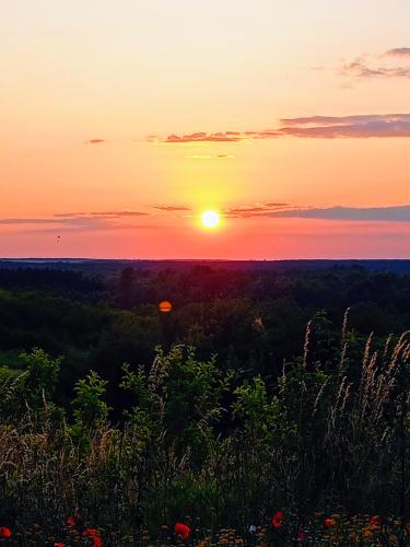 a sunset with the sun setting over a field at Siedlisko Panorama na Koncu Swiata - Całoroczny domek in Podgórz