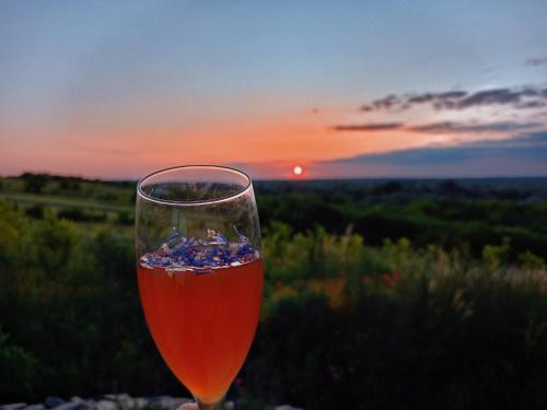 a glass of wine with the sunset in the background at Siedlisko Panorama na Koncu Swiata - Całoroczny domek in Podgórz