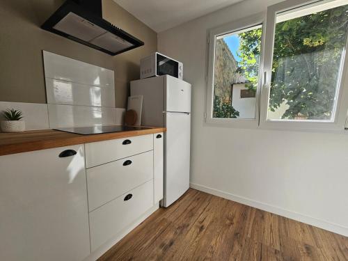 une cuisine avec un réfrigérateur blanc et une fenêtre dans l'établissement T2 climatisé à 50m du port et de la plage, à Mèze