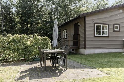 a table with an umbrella next to a house at Boats stay play lake cabin in Broby
