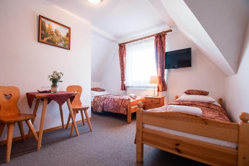 a bedroom with two beds and a table and a desk at Pokoje Gościnne Góraleczka in Szaflary