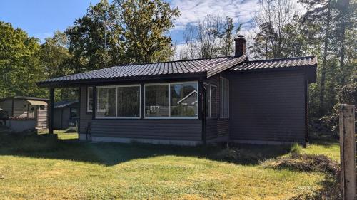 a small cabin with a roof on a grass field at Boats stay play lake cabin in Broby