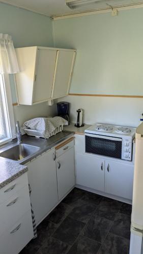 a kitchen with white cabinets and a stove top oven at Boats stay play lake cabin in Broby