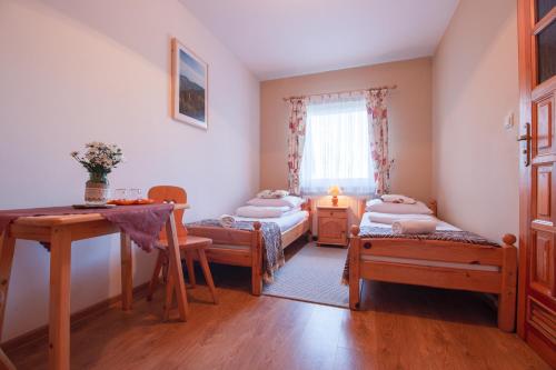 a room with two beds and a table and a window at Pokoje Gościnne Góraleczka in Szaflary