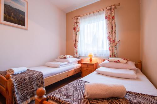two twin beds in a room with a window at Pokoje Gościnne Góraleczka in Szaflary