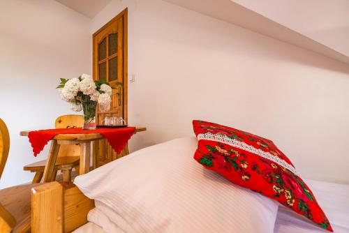 a bedroom with a bed with a red pillow and a table at Pokoje Gościnne Góraleczka in Szaflary