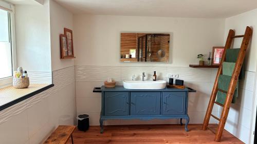 een badkamer met een blauwe wastafel en een spiegel bij Cottage MaarBurg in Ulmen
