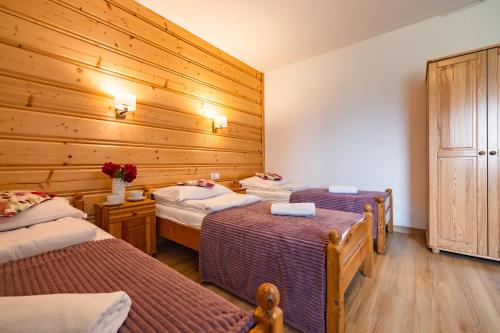 two beds in a room with wooden walls at Pokoje Gościnne Góraleczka in Szaflary