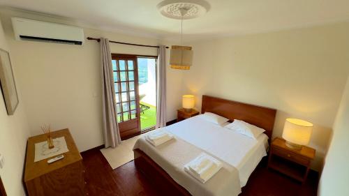ein Schlafzimmer mit einem weißen Bett und einem Fenster in der Unterkunft Miradouro 13 - Heated Pool in Vieira do Minho