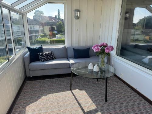 a porch with a couch and a glass table at Renovated family home with jacuzzi in Sandnes