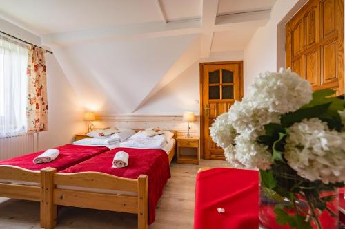 a bedroom with two beds and a red blanket at Pokoje Gościnne Góraleczka in Szaflary