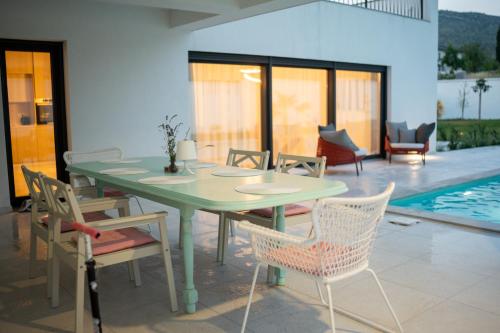 a green table and chairs in a patio with a pool at Villa Alba - Countryside Hideway Between Mostar & Blagaj 