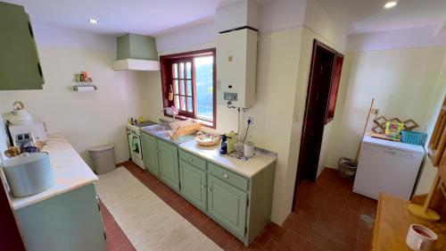 eine Küche mit grünen Schränken und einem Fenster in der Unterkunft Miradouro 13 - Heated Pool in Vieira do Minho