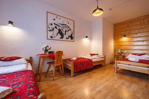 a bedroom with two beds and a desk in it at Pokoje Gościnne Góraleczka in Szaflary