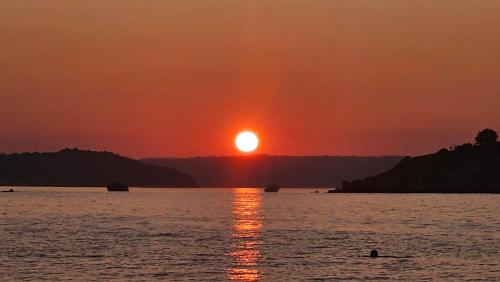 a sunset over a body of water with the sun setting at Villa YOLO in Almirida