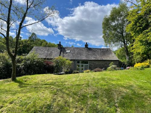 a house on a hill with a grassy yard at The Barns Low Stott Park near Lake Windermere in Ulverston