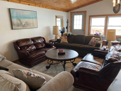a living room with leather furniture and a table at Peaceful Cayuta Lake Cottage with early check in in Alpine