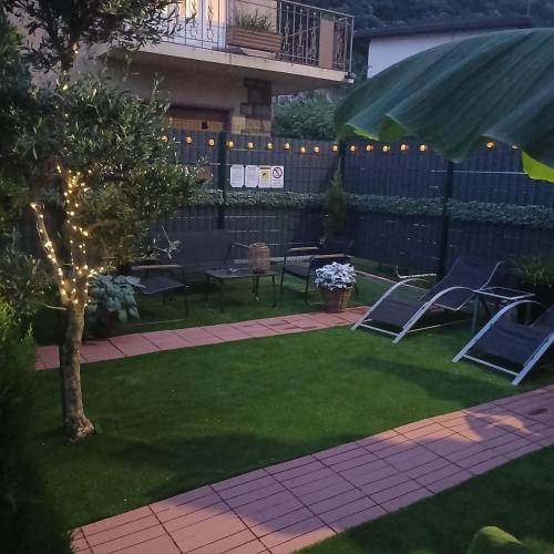 a yard with chairs and a tree and a fence at TROPICAL HOME PORTO CERESIO in Porto Ceresio