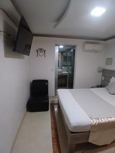 a bedroom with a bed and a black chair at Hotel Plaza Norte Cali in Cali