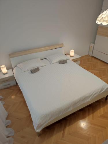 a large white bed in a room with two lights at Apartman Doma in Livno