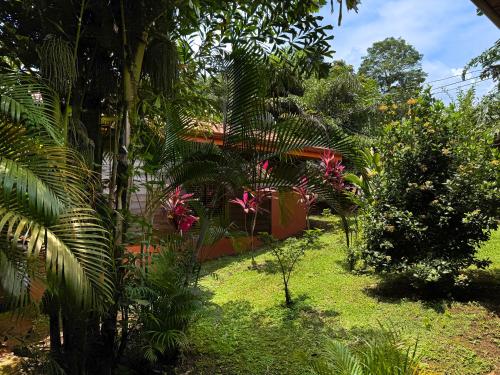 a garden with trees and flowers in front of a house at Hotel Heliconias Nature Inn & Hot Springs in Fortuna