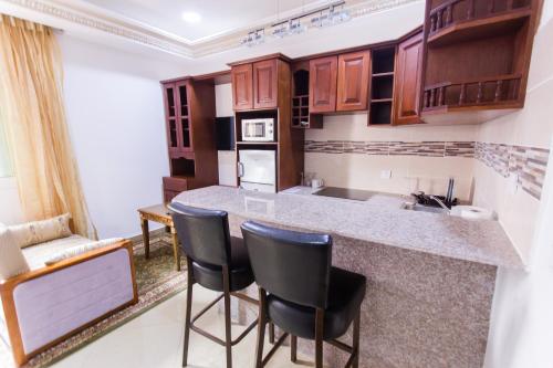 - une cuisine avec un comptoir et des chaises dans la chambre dans l'établissement Appartement Résidence le Jomonia, à Libreville