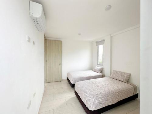 a white room with two beds and a window at Apartment for 8 Guests in Sabanilla a few steps from the Sea in Maizal