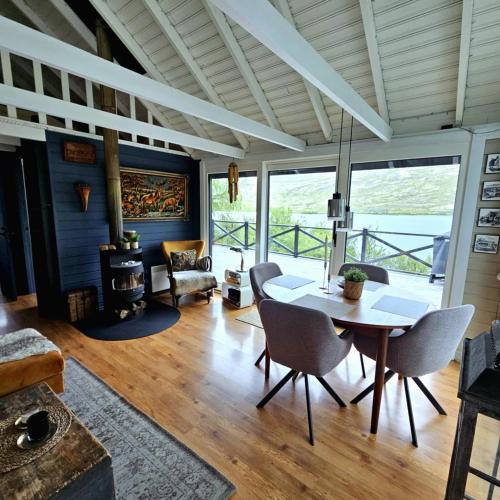 a living room with a table and chairs and a large window at Lakefront cottage with jacuzzi in Borgarnes