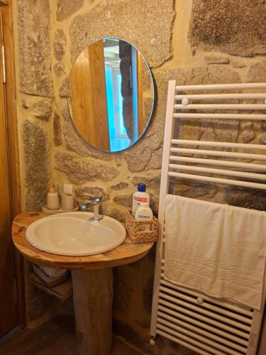 a bathroom with a sink and a mirror on a stone wall at Casa Carballo in Puxedo