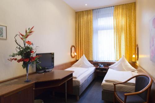 ヴュルツブルクにあるトップ ホテル アムバーガーのベッド2台とデスクが備わるホテルルームです。