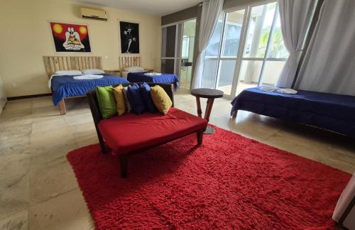 a living room with a red chair and a red rug at Pousada Ceará - Porto das Dunas in Aquiraz