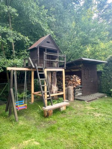 a tree house with a ladder in the yard at Chata Roda s vnitřní saunou in Rabyně