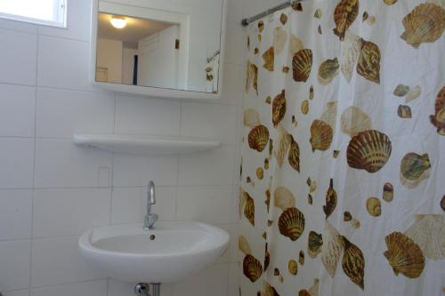 ein Bad mit einem Waschbecken und einem Duschvorhang in der Unterkunft Orange Rembrandt Studio Apartments in Willemstad