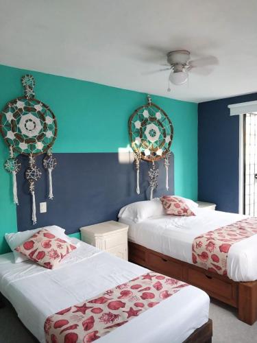 two beds in a room with green and blue walls at Casa de 4 habitaciones con alberca in Barrio Nuevo