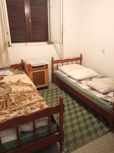 two twin beds in a room with a table at Braco apartmani Utjeha in Kravlja