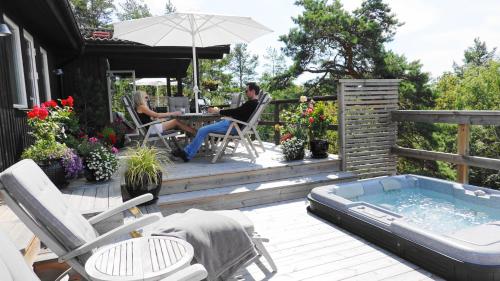 a man sitting on a deck next to a hot tub at 5-star homestay for 2 with breakfast, hot-tub, aircon and bikes in Ingarö