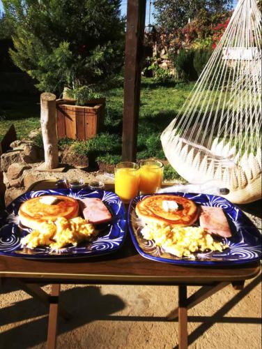 een tafel met twee borden met ontbijtproducten erop bij Roca Jardin Chalet in Valle de Guadalupe