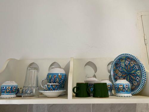 a shelf with blue and white cups and plates on it at Studio de charme ⵣ in Houmt Souk