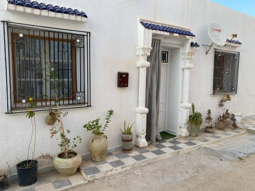 a white house with potted plants in front of a door at Studio de charme ⵣ in Houmt Souk