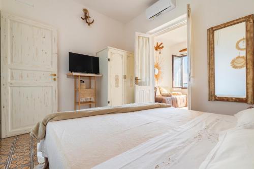 a bedroom with a large white bed and a mirror at B&B Steddueoro in Baunei