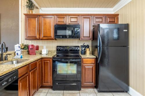 ピジョン・フォージにあるFun Retreat w Pool Table Hot tub & Grillのキッチン(黒い冷蔵庫、木製キャビネット付)